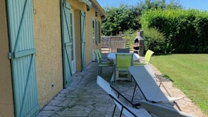 A patio with stone flooring, a table, and two chairs. - Single-storey house, pets welcome - 6 guests (Caulaincourt)
