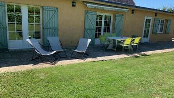 A building with a patio area featuring outdoor furniture, including chairs and a table.