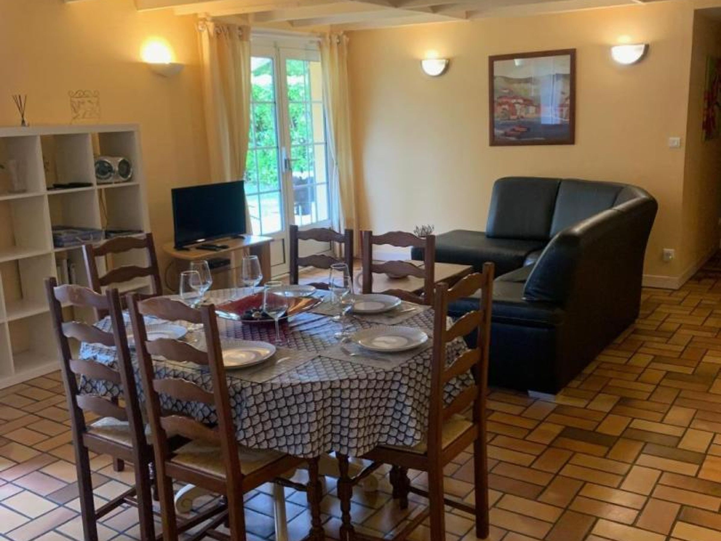 Un coin repas avec une table ronde dressée pour quatre personnes, entourée de chaises en bois.