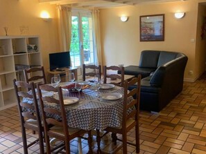 A dining area with a round table set for four, surrounded by wooden chairs.