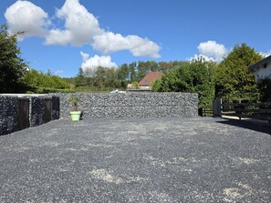 Un espacio al aire libre empedrado con un muro de piedra, una valla de madera y una planta en maceta.