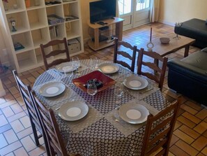 Un coin repas avec une table ronde dressée pour quatre personnes, entourée de chaises en bois.