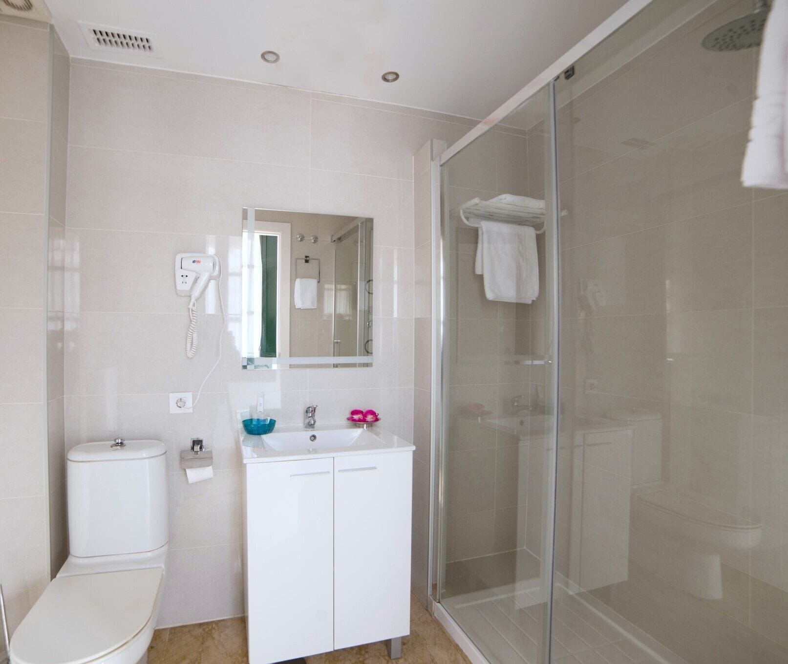 A modern bathroom with a toilet, sink, and glass shower enclosure.