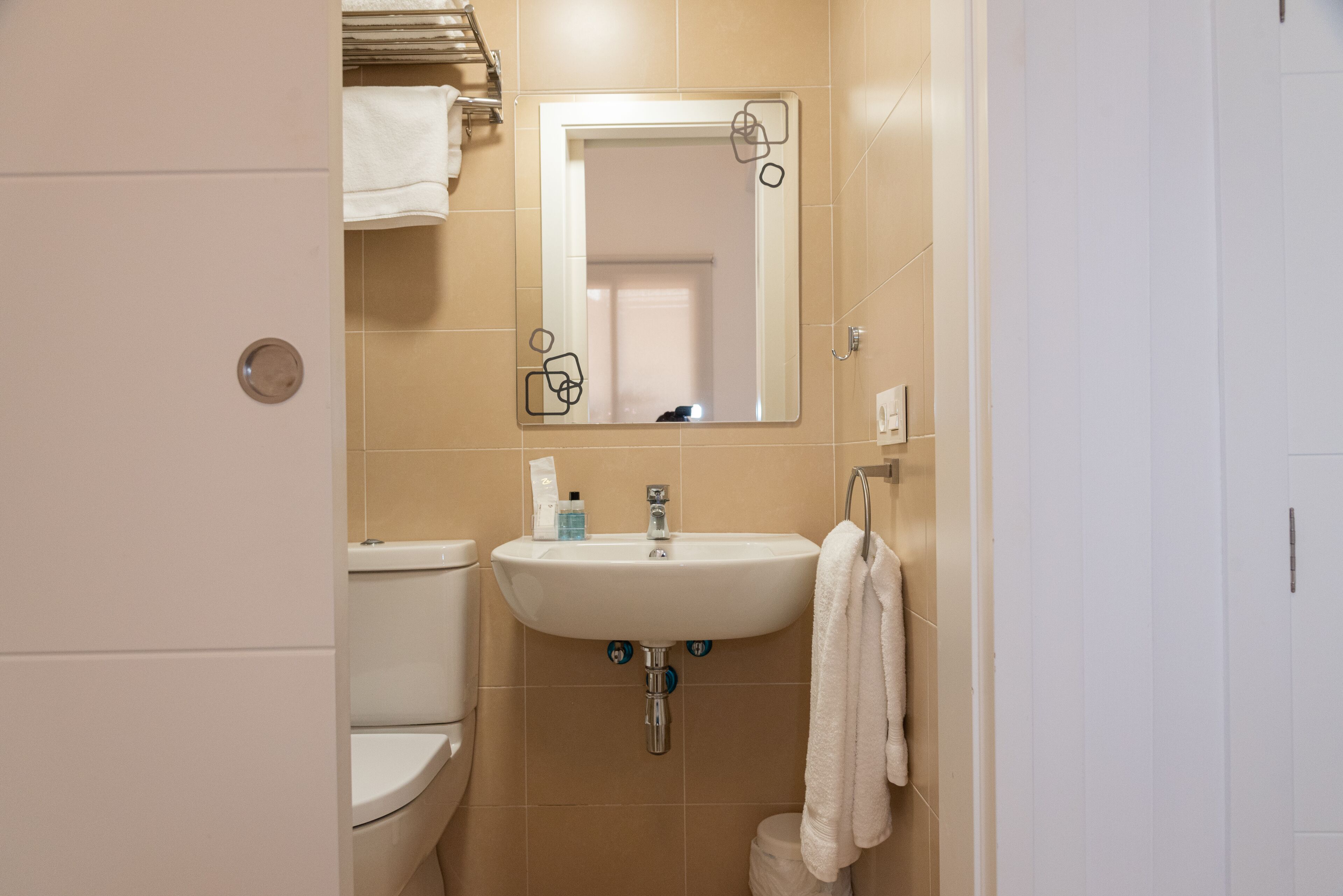 A bathroom with a white sink, mirror, and toilet.