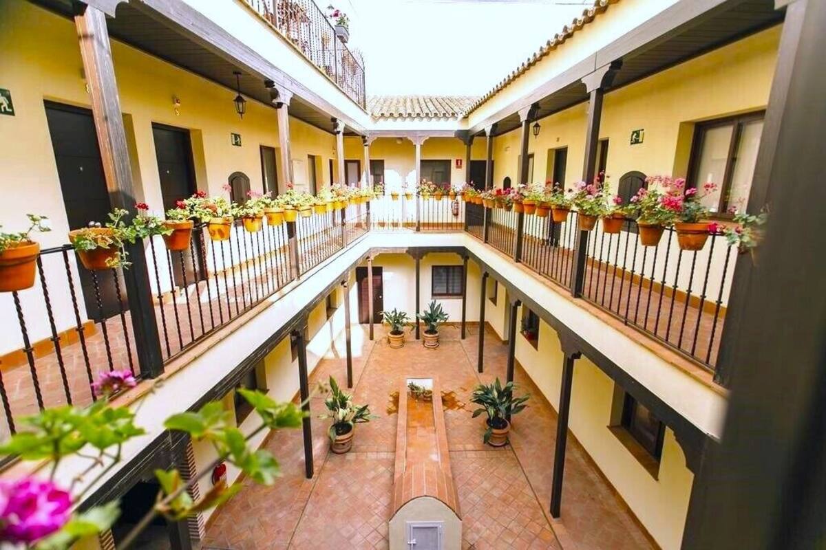 A courtyard with a central open space surrounded by balconies, each with potted plants.