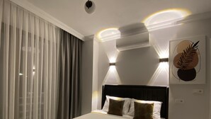A modern hotel room with a large bed, a ceiling light fixture, and a wall-mounted air conditioner. - Bavella House Pamukkale (Denizli)