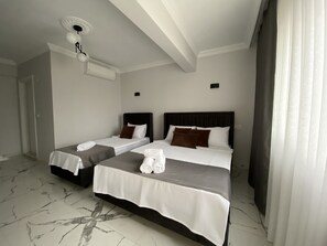 Une chambre d’hôtel avec deux lits, un ventilateur de plafond et un sol en marbre.