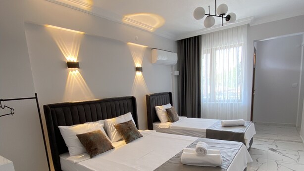 A modern hotel room with two beds, marble flooring, and wall-mounted lighting. - Bavella House Pamukkale (Denizli)