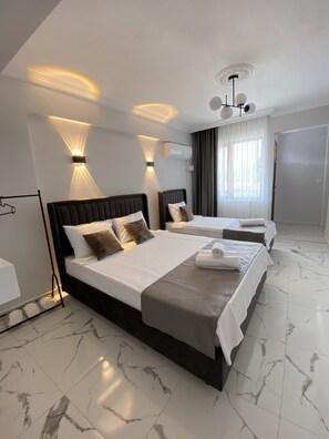 Une chambre d’hôtel moderne avec deux lits, un sol en marbre et des luminaires fixés au mur.