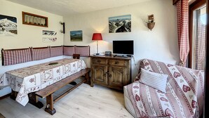 Ein gemütliches Zimmer mit einer hölzernen Bank, einer Couch, einem Fernseher und Wandbildern.