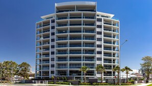 A multi-story hotel with a curved facade, balconies on each floor, and a sign indicating the name "The Cove". - Cove 601 - Luxury living in Forster. (Forster)