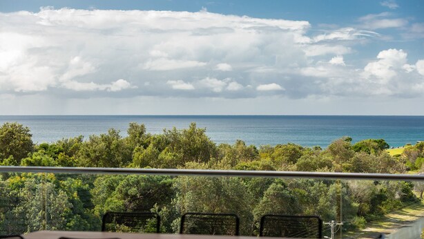 A view of the ocean from a balcony with lush greenery in the foreground. - Cove 601 - Luxury living in Forster. (Forster)