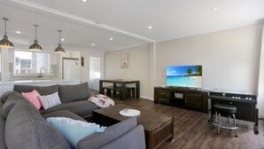 A modern living room with a sofa, coffee table, TV, and bar area. - River Tonic - stunning views of the Myall River (Tea Gardens)