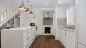 A modern kitchen with white cabinetry, stainless steel appliances, and pendant lighting. - River Tonic - stunning views of the Myall River (Tea Gardens)