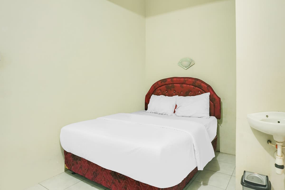 Un dormitorio con cama, mesita de noche, luz empotrada en la pared y lavamanos.