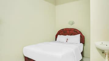 A bedroom with a bed, a bedside table, a wall-mounted light, and a sink.
