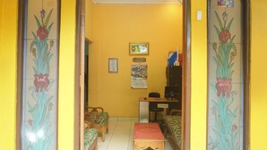 Una habitación con paredes amarillas, un escritorio de madera, dos sillas, una cama y una mesita.