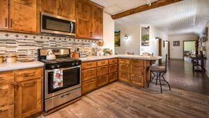 Una cocina con gabinetes de madera, estufa de acero inoxidable y microondas.