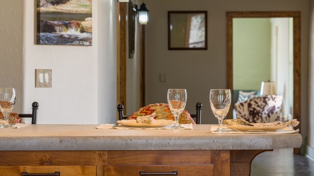 Una encimera de cocina con una isla de piedra, dos copas de vino y un plato con una servilleta.