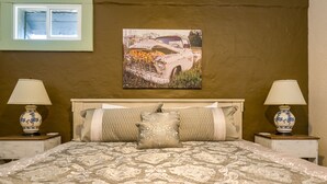 Un dormitorio con una cama grande, dos lámparas de noche, un cabecero y un cuadro en la pared.