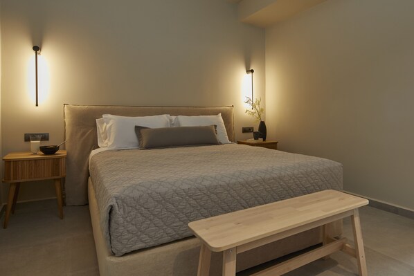 A neatly arranged bedroom with a bed, bedside tables, a bedside lamp, and a small wooden bench.