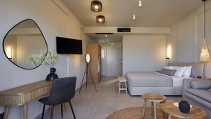 Una habitación de hotel moderna con cama, sofá, escritorio, silla y un espejo grande.