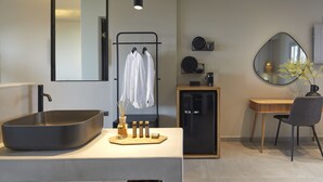 Un baño moderno con un lavamanos grande y rectangular, un mueble negro, un tocador de madera y un espejo.