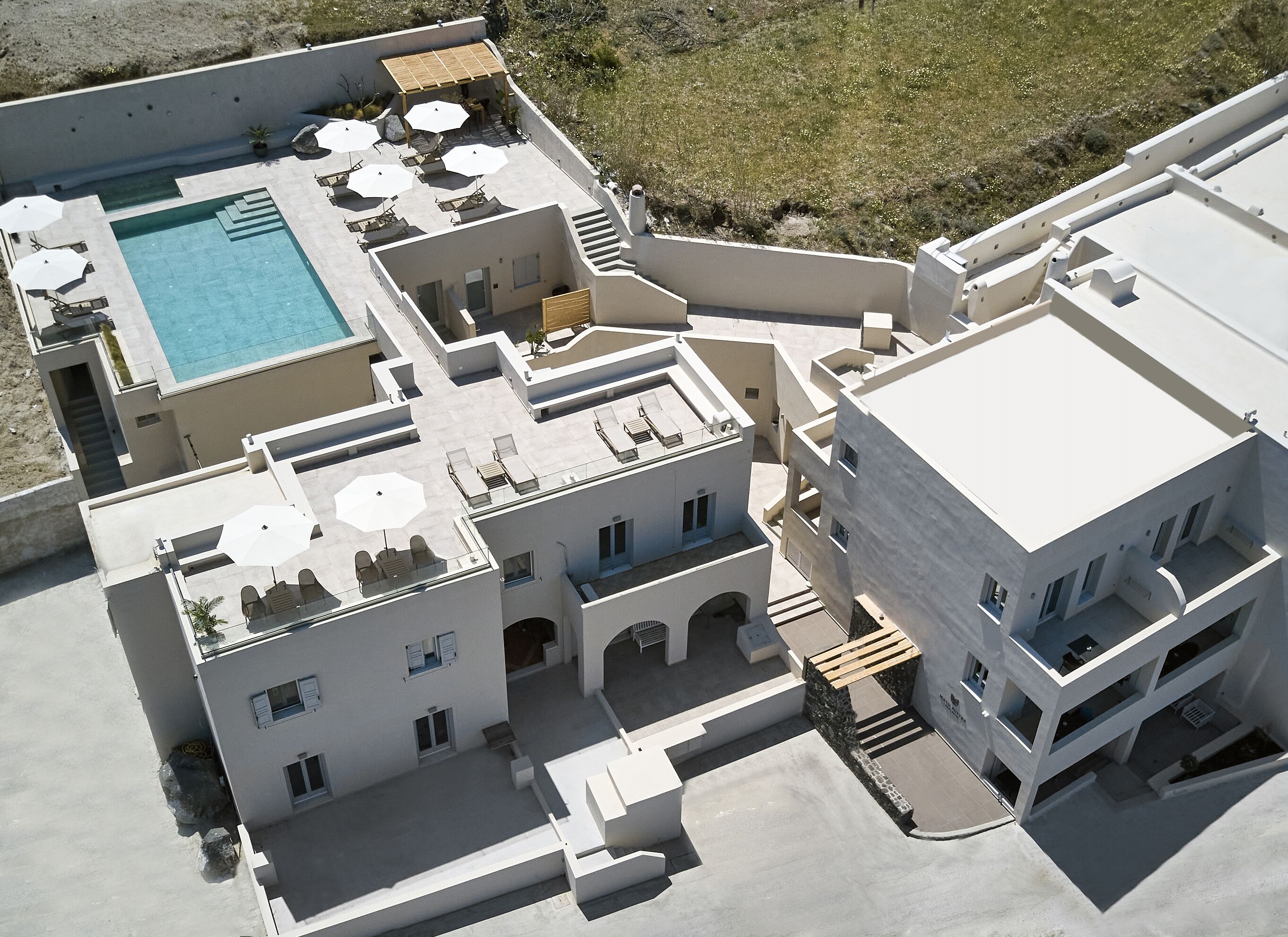 Vista aérea de un hotel con piscina, varios balcones y zonas de estar al aire libre.