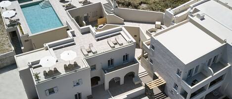 Vista aérea de un hotel con piscina, varios balcones y zonas de estar al aire libre.