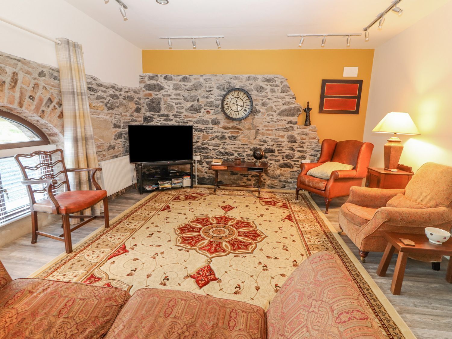 Ein Wohnzimmer mit Steinwand, großem Teppich, Fernseher und Kamin.