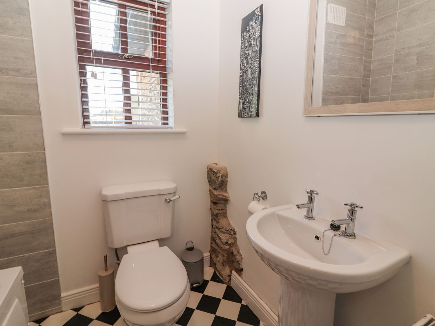 Baño con inodoro, lavamanos y ventana con persianas.