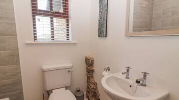 Baño con inodoro, lavamanos y ventana con persianas.