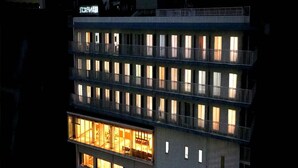 A multi-story hotel with illuminated windows and balconies, featuring a sign in a foreign language. - Jisco Hotel Obama Onsen (Unzen)