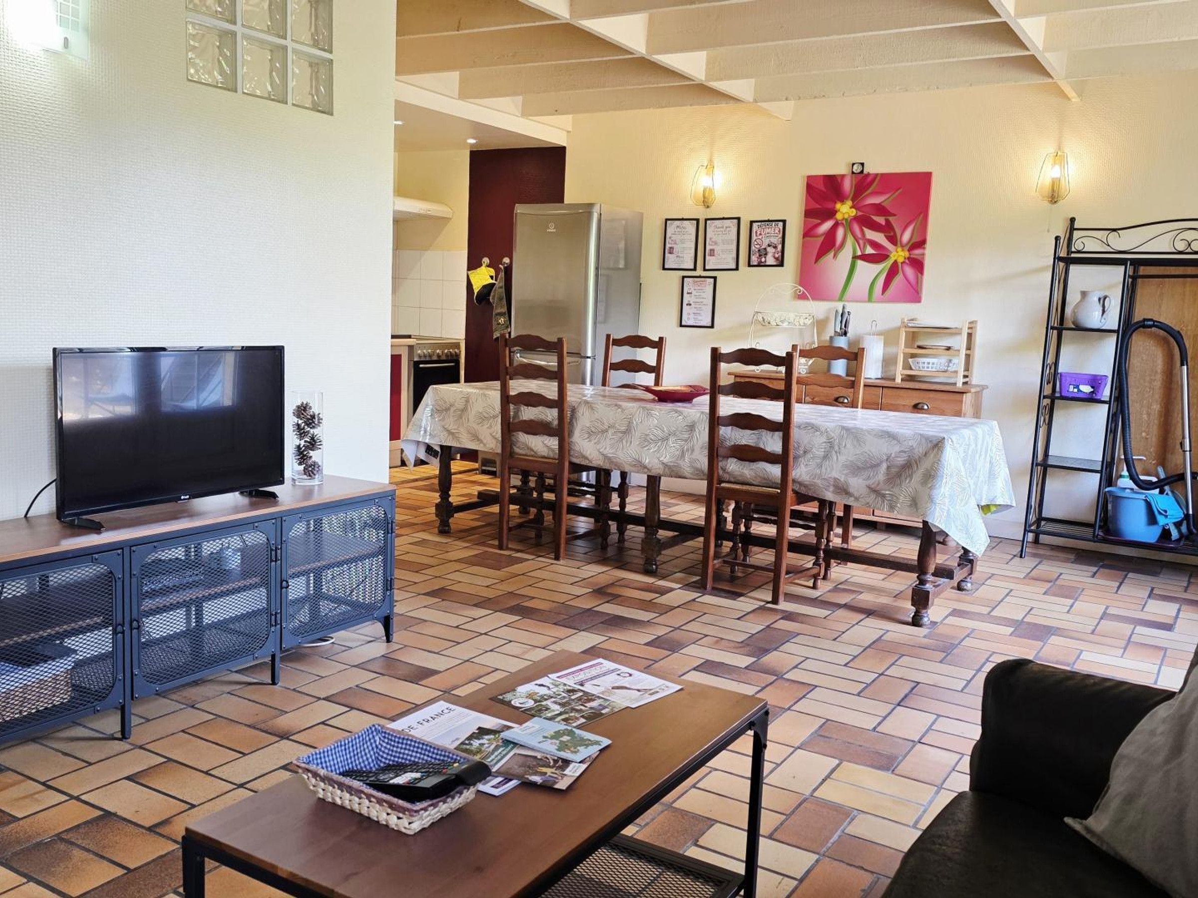 A living room with a television, dining table, chairs, and a coffee table.