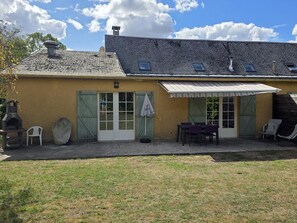 A building with a sloped roof, a covered patio area with outdoor seating, and a chimney.