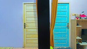 A room with a closed yellow door, a blue door, and a small shelf with Hello Kitty toys. - Hotel O Adam Kost SyariahNearWisata Jembatan Barito (Alalak)