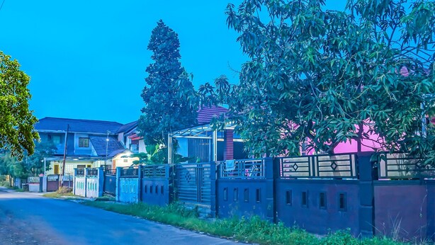 A residential street with houses, a gated entrance, and a clear sky. - Hotel O Adam Kost SyariahNearWisata Jembatan Barito (Alalak)