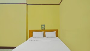 A neatly made bed in a room with yellow walls and a wooden headboard. - Hotel O Adam Kost SyariahNearWisata Jembatan Barito (Alalak)