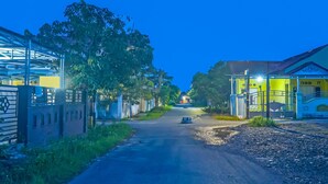 A street view at dusk with buildings on either side, a clear sky, and a vehicle in the distance. - Hotel O Adam Kost SyariahNearWisata Jembatan Barito (Alalak)