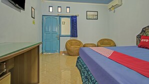 Une chambre à coucher avec un lit, un bureau, une télévision, une porte et une fenêtre.