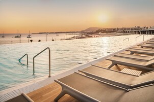 Una piscina al aire libre, sombrillas, tumbonas