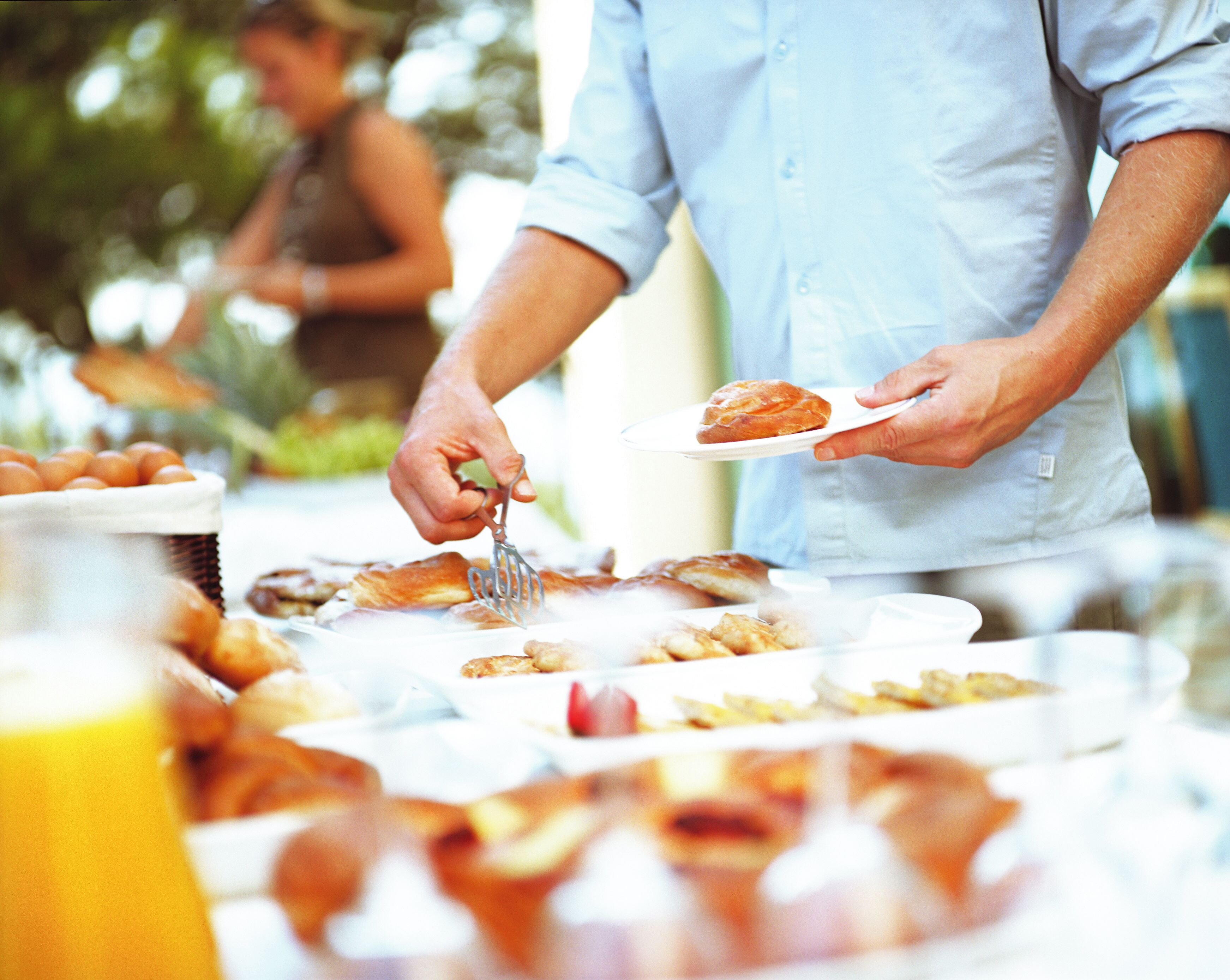 A buffet with various food items and a person serving themselves.