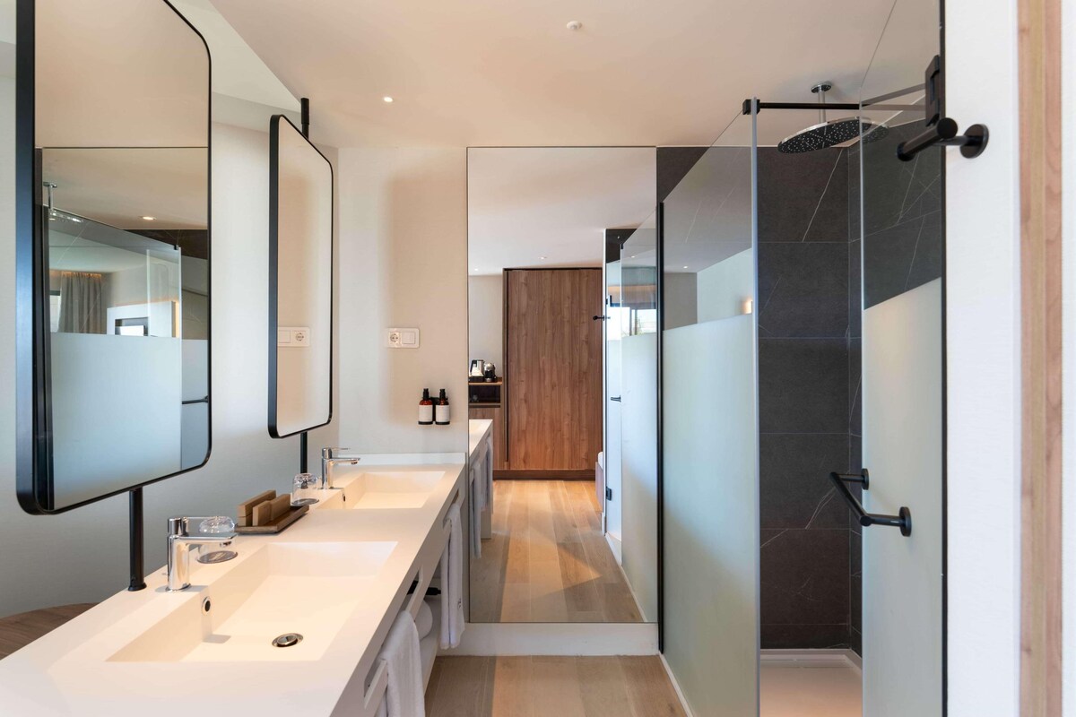 Een moderne badkamer met een grote spiegel, een douche en een wastafelmeubel met een wastafel.