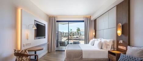 Une chambre d’hôtel comprenant un lit, un canapé, un bureau, une chaise, une télévision et une vue sur l’extérieur.