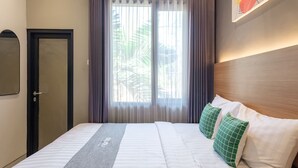 A hotel room with a bed, a door, and a window with curtains. - Mono Coliving Pakis, Surabaya (Surabaya)