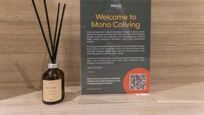 A welcome sign for Mono Coliving with a QR code and a bottle of sea salt incense. - Mono Coliving Pakis, Surabaya (Surabaya)