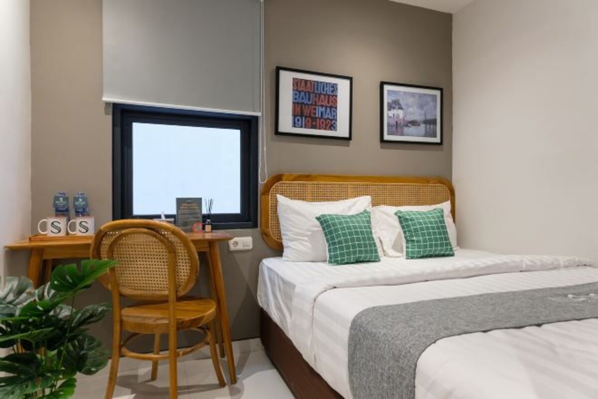 Een slaapkamer met een bed, een bureau, een stoel en een raam.