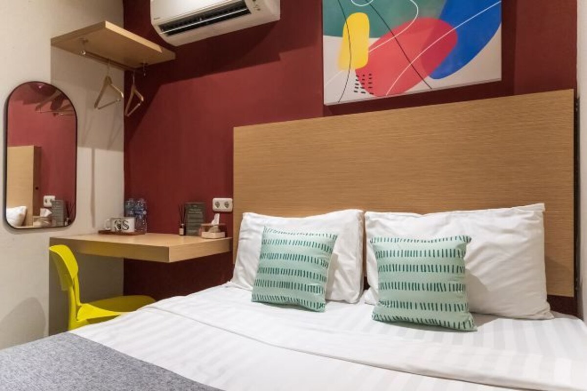 Een hotelkamer met een bed, een bureau, een stoel en een wandairconditioner.