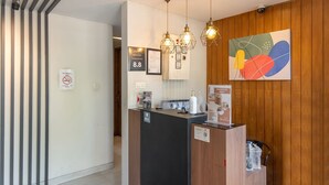 A reception area with a wooden panel wall, a black reception desk, and a modern chandelier. - Mono Coliving Pakis, Surabaya (Surabaya)