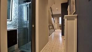 A hallway with a glass shower door, a staircase, and a tiled floor. - Bellerose 6 (Lancaster)